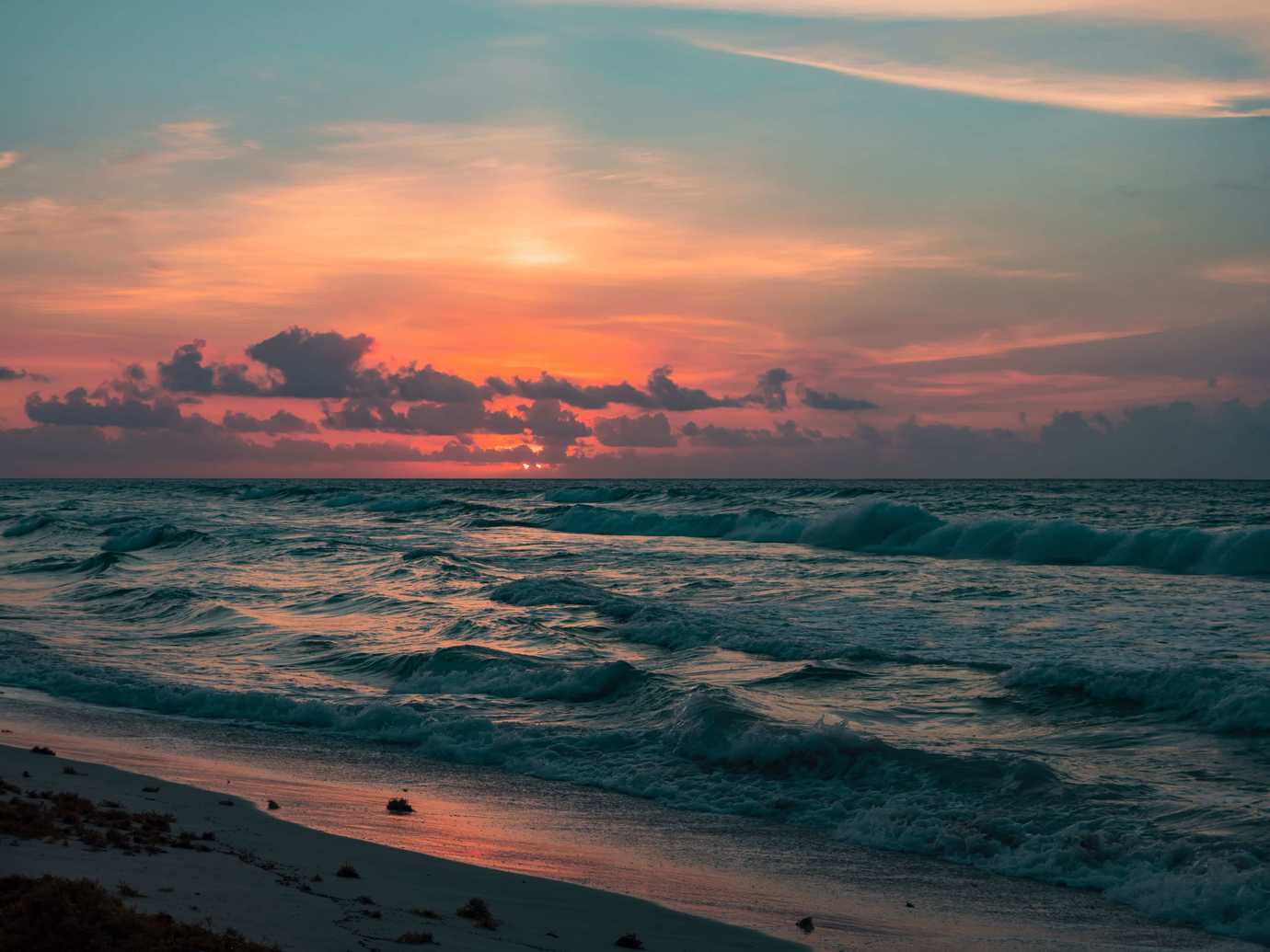 A beach at sunset with crashing waves.